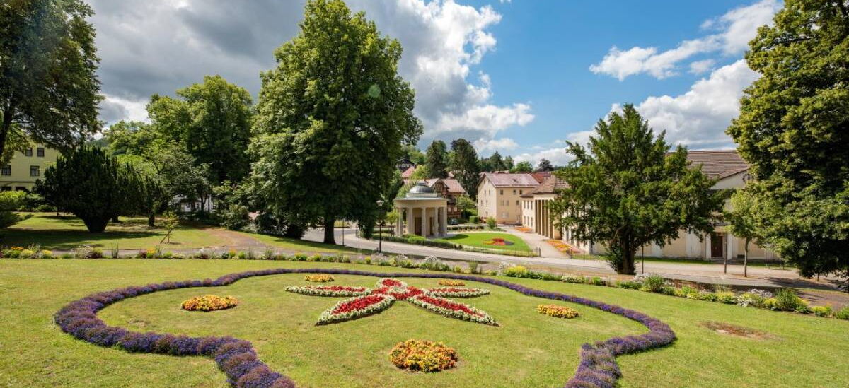 Landschaftsaufnahme Historischer Kurpark mit Bepflanzung, Comödienhaus und Brunnentempel